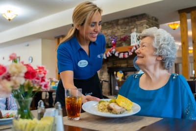 Staff serving a meal to a resident in the dining area