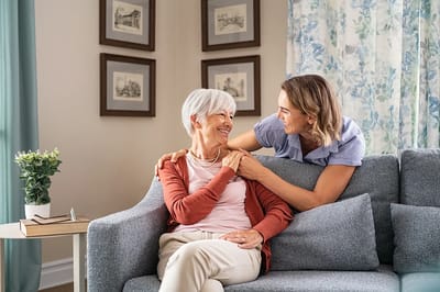 A caregiver and resident sharing a joyful moment on a couch