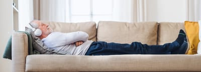 An older man resting on a couch with headphones