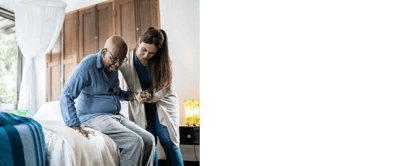 Staff assisting a resident in a warmly lit bedroom