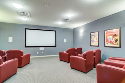 Interior of a cozy movie theater room with red chairs
