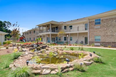 Exterior view of a senior living facility with a pond