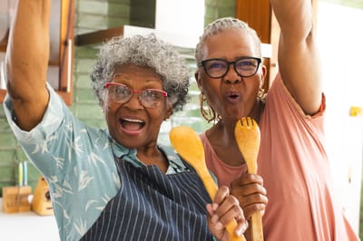 Two residents joyfully cooking together in a kitchen