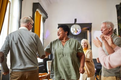 Residents and staff dancing together in a common area