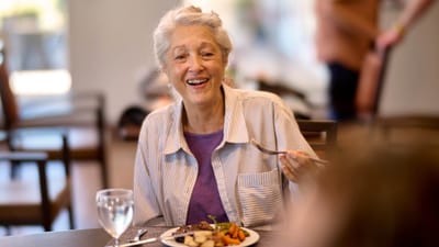 A smiling resident enjoying a meal in the dining area