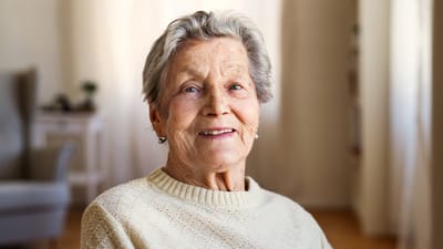A smiling elderly resident in a cozy interior