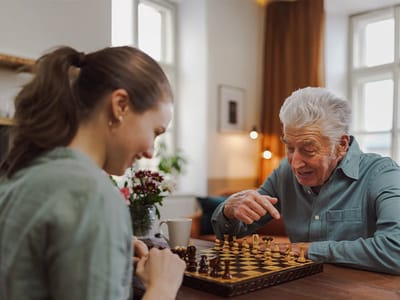 Resident and staff member playing chess together