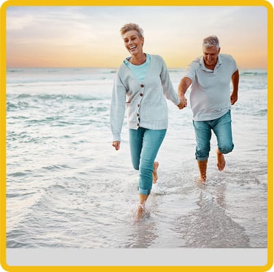 Two seniors playing on the beach at sunset