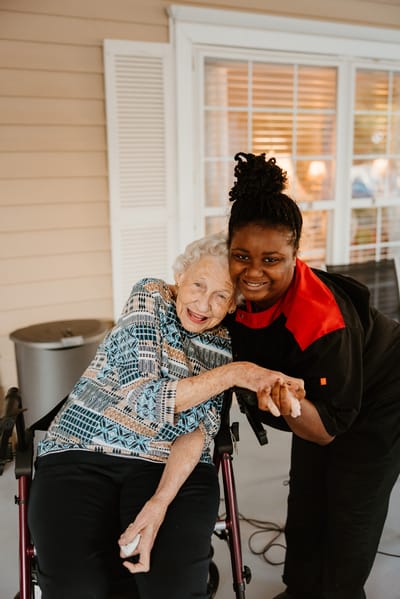 A caregiver and a resident smiling together outdoors