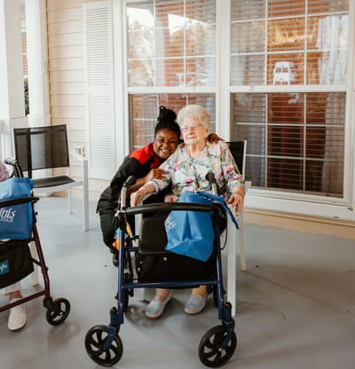A staff member posing with a resident on a porch