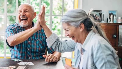 Two seniors joyfully engaging in a card game indoors