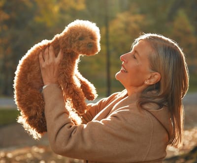 Woman smiling holding a small dog outdoors