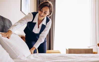 Staff member arranging bed linens in a clean room