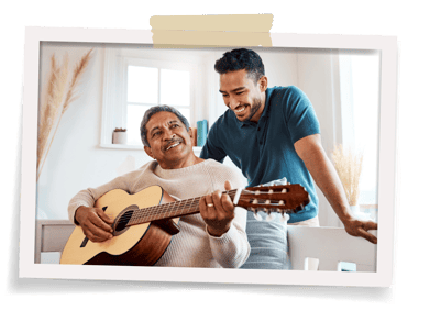 Resident playing guitar with staff member in a bright room