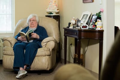 Resident reading in a cozy chair in a common area