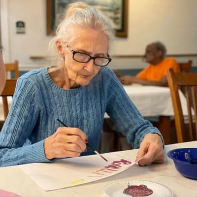 An elderly woman painting during an activity session