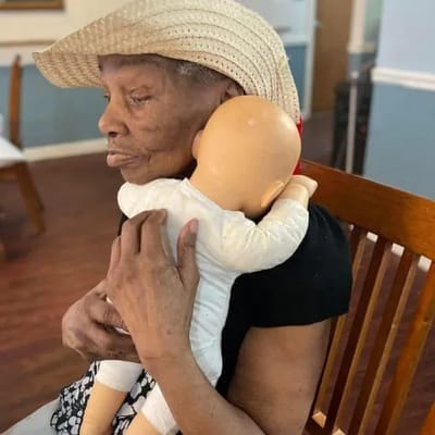 Resident holding a doll in a cozy sitting area