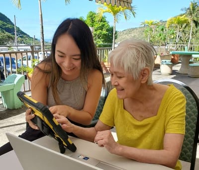 A staff member helping a resident with a tablet outdoors
