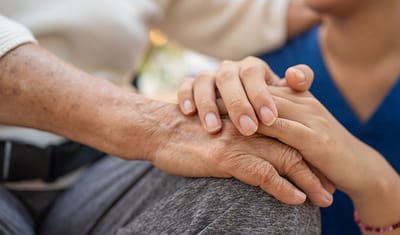 A caregiver holding the hand of an elderly resident
