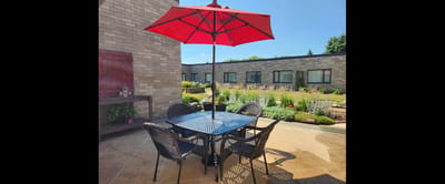 Outdoor seating area with a red umbrella and garden view