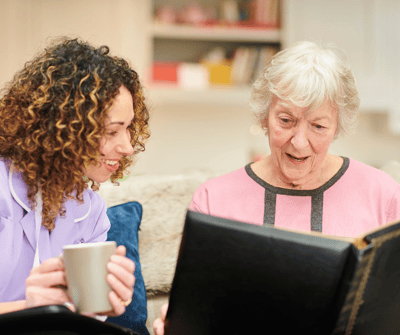 A caregiver and resident looking at a photo album together