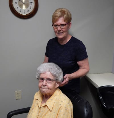 Staff member styling resident's hair in a salon