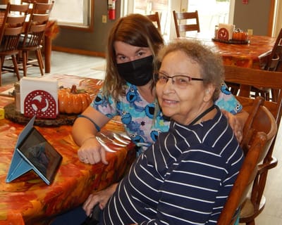 A staff member assisting a resident at a dining table
