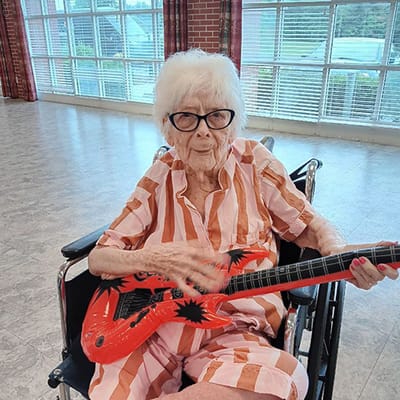 Resident playing a toy guitar in an activity room