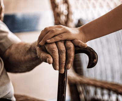 Elderly hands grasped gently by a younger hand.