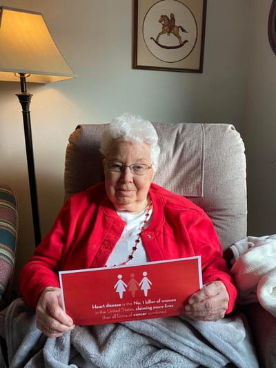 Resident holding a sign in a cozy chair.
