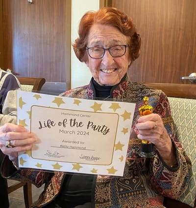 Resident celebrating with an award and certificate