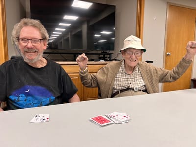 Two senior men playing cards and celebrating.