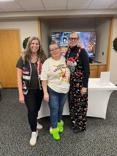 Three staff members in festive attire during holiday celebration