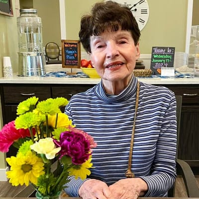 Resident smiling in a common area with flowers