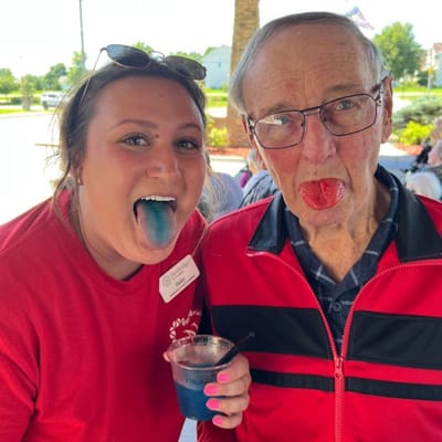 Staff and resident showing colorful ice pops in an outdoor setting