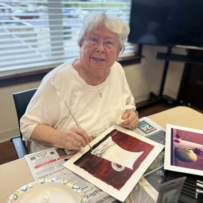 A resident painting in a bright activity room