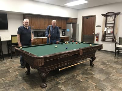 Two residents playing billiards in a common area