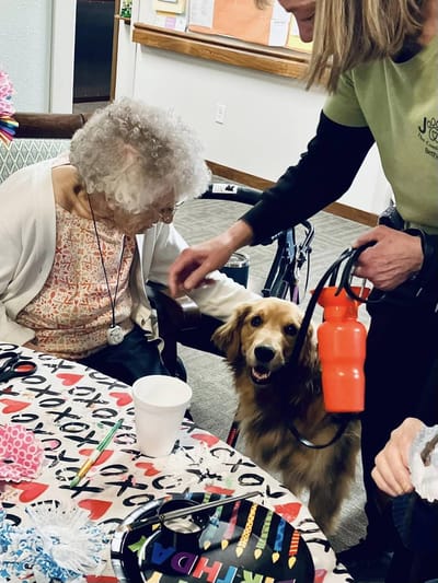 Resident interacting with a staff member and a dog