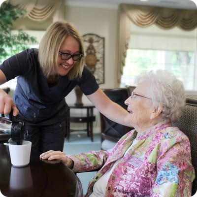 Staff pouring coffee for a smiling resident