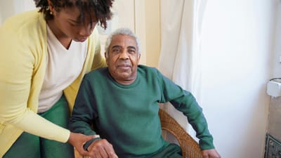 Caregiver assisting a senior man in an indoor setting