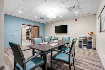 A modern activity room with tables and chairs