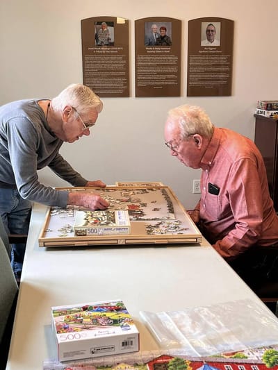 Two residents working on a puzzle at a table
