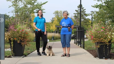 Resident and staff member posing with a dog in a garden