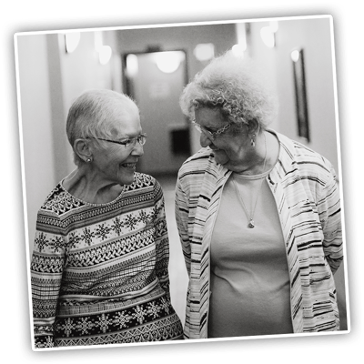 Two residents smiling and walking in a hallway