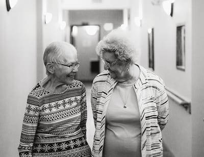 Two smiling residents chatting in a hallway