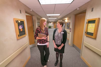 Two staff members chatting in a facility hallway
