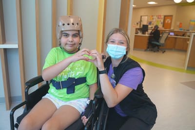 A child and caregiver making a heart shape with their hands