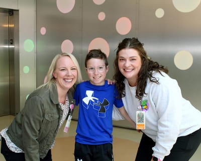 Three smiling individuals in a colorful interior space