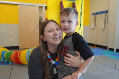 Staff member holding a child in a colorful activity room