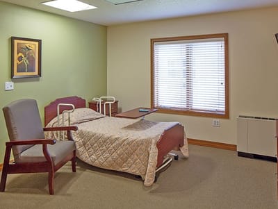 A private resident room with a bed and chair